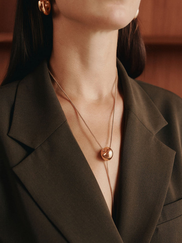 Roségoldene PURELEI Kette mit rundem Anhänger, elegant getragen mit Blazer.