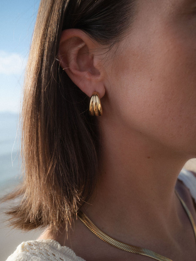 Fused Ohrringe von PURELEI, goldene Creolen-Dreier-Optik, elegant getragen am Ohr im natürlichen Tageslicht.