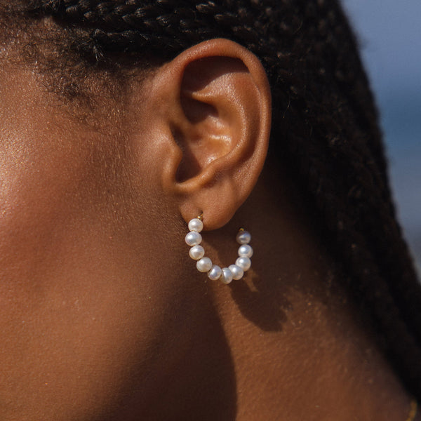 PURELEI Aina Ohrringe mit goldfarbenen Creolen und zarten Perlen, elegant und feminin im warmen Tageslicht